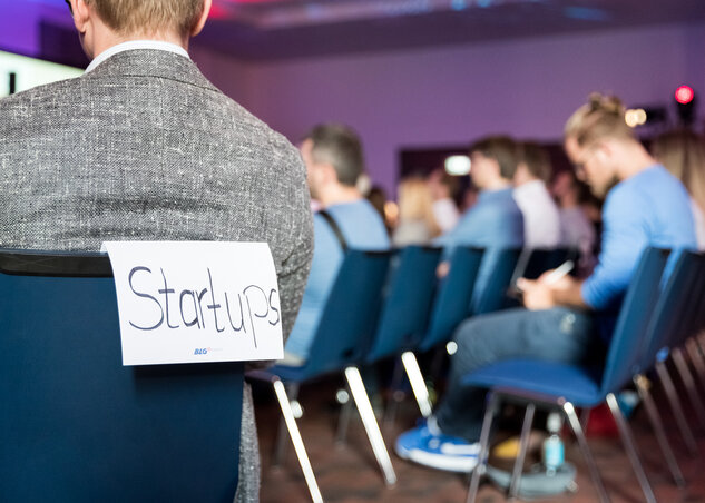 Viele junge Menschen sitzen auf Stühlen.